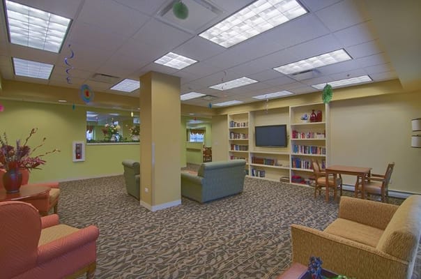 Lounge area with seating and bookshelves in a senior living facility