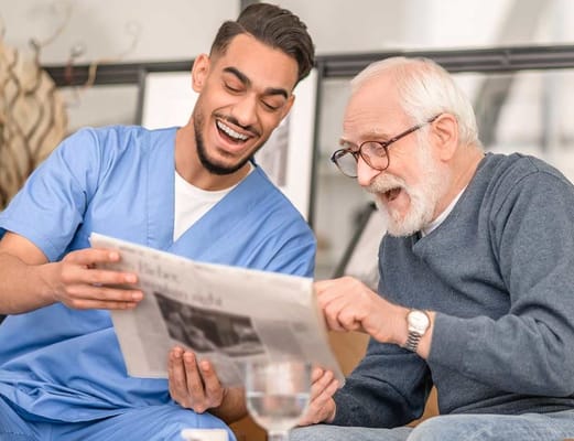 Staff member and senior resident enjoying a newspaper