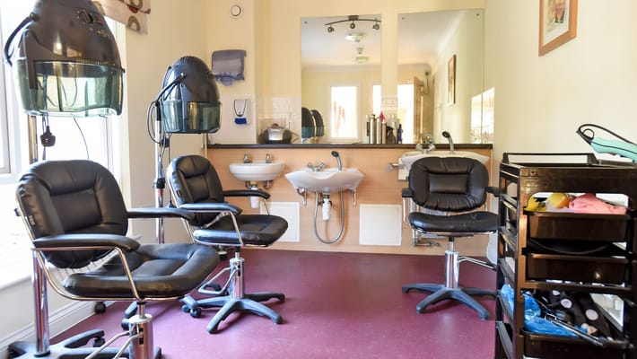 Interior view of a hair salon with styling chairs and hairdryers.