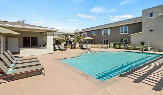Outdoor pool area with lounge chairs and shaded seating