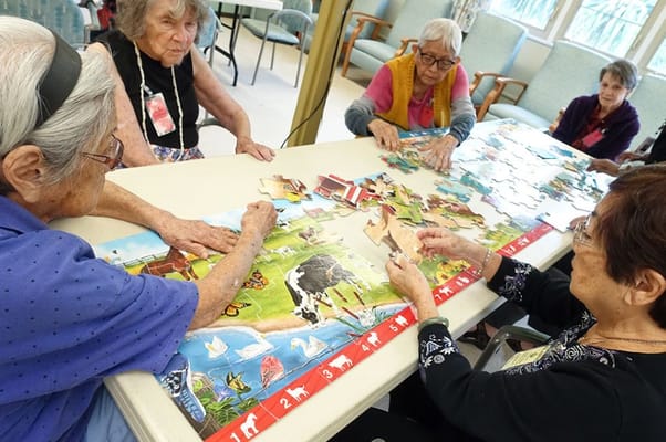 Residents engaging in a puzzle activity at a common table