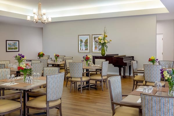 Bright dining room with flowers and a piano