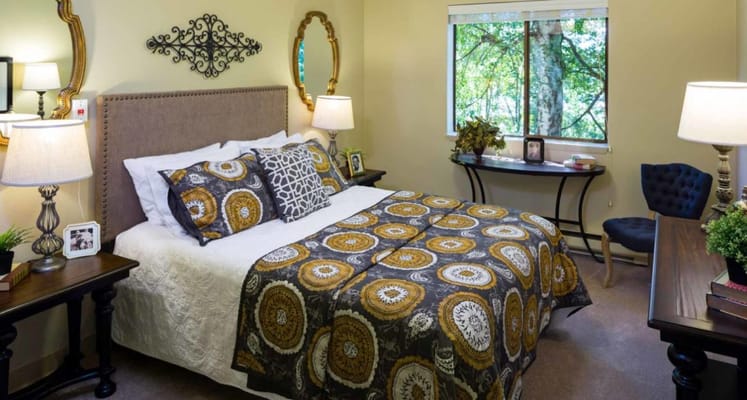 Bedroom featuring a bed with patterned bedding, nightstands, and a window