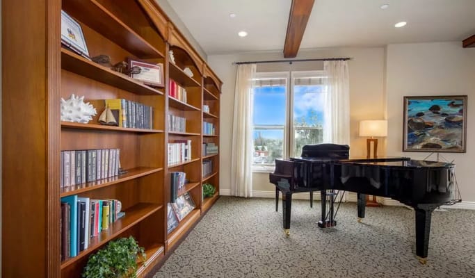 Interior view of a common area with a piano and bookshelves