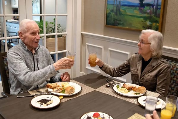Residents toasting with drinks at a dining table