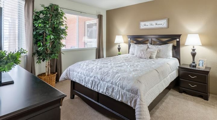 Cozy bedroom featuring a bed, bedside tables, and decorative plants