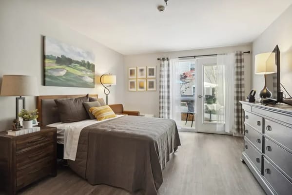 A cozy bedroom with a bed, dresser, and balcony access.