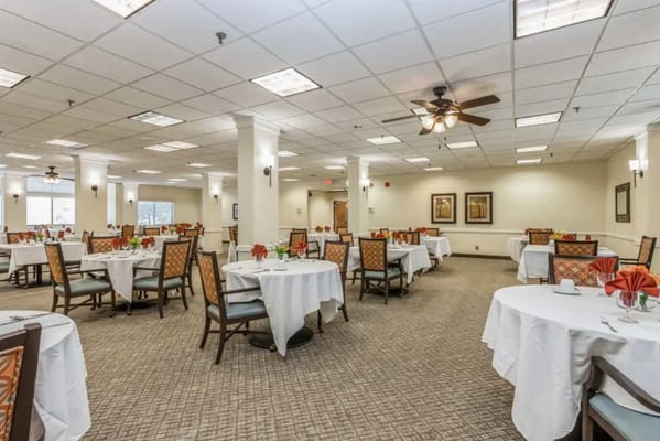 Spacious dining room with round tables set for meals.
