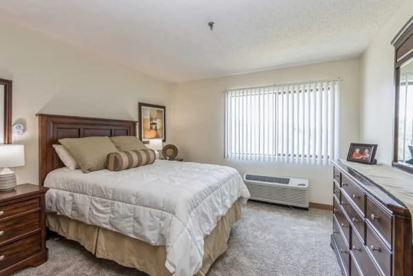 Bright and inviting bedroom with a bed, dresser, and window blinds