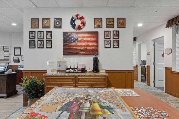 A common area featuring a puzzle table, patriotic decor, and displayed photos.