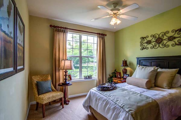Well-decorated bedroom featuring a bed, lamp, and window with a view.