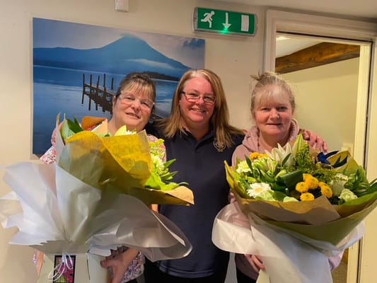 Staff and residents with flower bouquets in an interior space