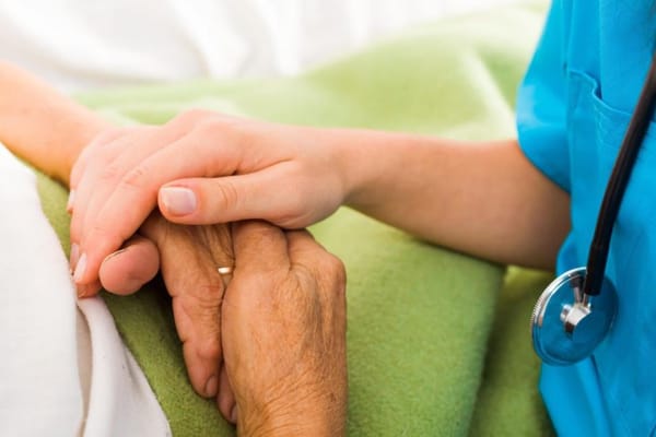 Caregiver holding a senior's hand