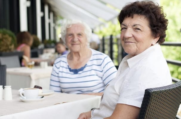 Two elderly women enjoying coffee on a patio