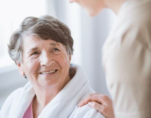 A caregiver smiling at a resident in a cozy interior