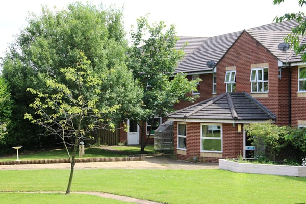 Exterior view of Millfield Care Home and surrounding garden