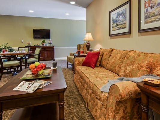 A cozy living room with a sofa, table, and dining area in Regent Park Assisted Living.