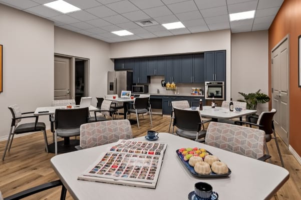 Bright dining area with tables, chairs, and a kitchenette.