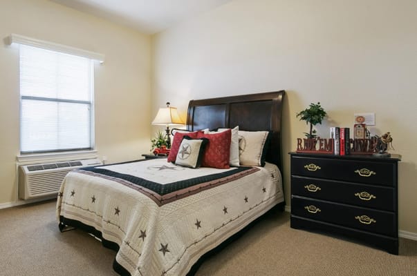 A cozy bedroom with a bed, dresser, and window.