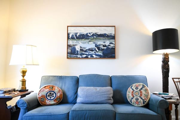 Living room featuring a blue sofa, decorative pillows, and artwork