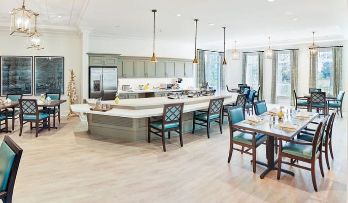 Spacious dining area with tables and a kitchen in The Sheridan at Hobe Sound
