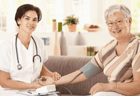 Nurse taking a senior's blood pressure in a cozy living room