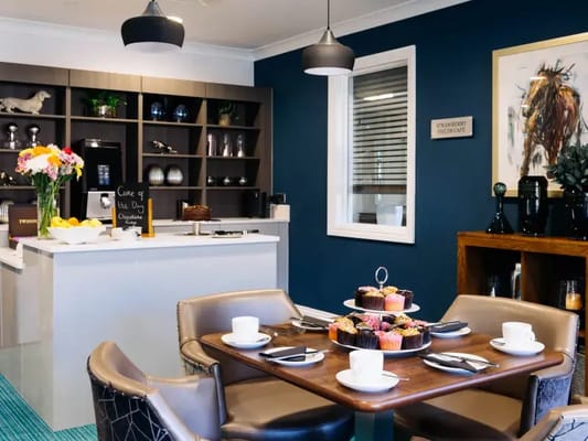 Brightly decorated cafe with a table of cupcakes and floral arrangements