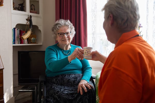 A resident and a caregiver sharing a cup of tea.