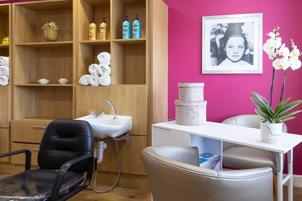 A cozy beauty room featuring a black chair, storage shelves, and decorative elements.