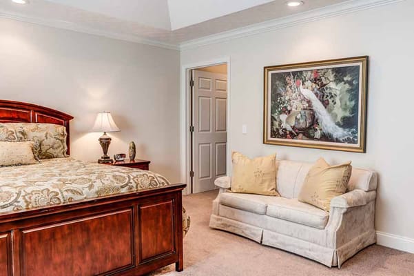 A well-furnished bedroom with a bed, lamp, and a small couch