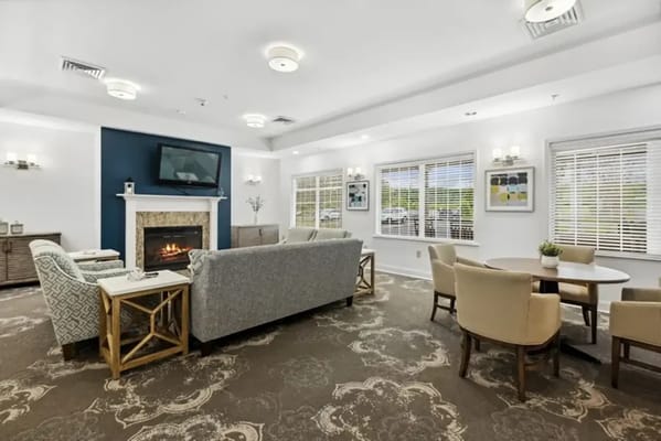 A cozy living room featuring a fireplace, comfortable seating, and large windows.
