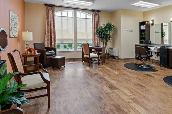 A salon area with chairs, plants, and large windows.