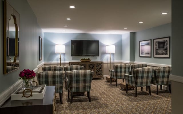 A cozy living room with plaid chairs, a TV, and lamps.