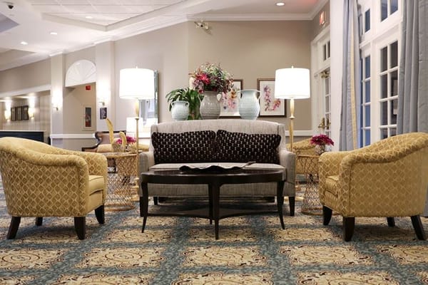Inviting seating area in a senior living facility lobby with decorative plants and soft lighting.