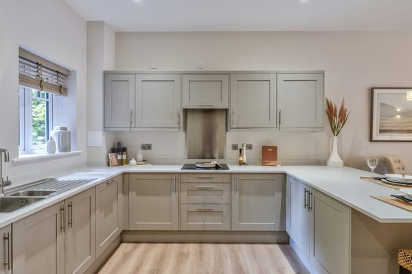 A spacious modern kitchen with grey cabinets and a bright window.