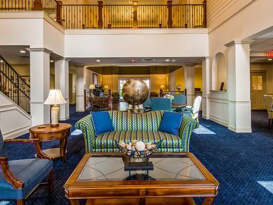 A cozy living room with a striped couch, wooden tables, and a decorative globe in a senior living facility.