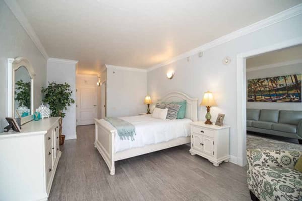 Spacious bedroom with a bed, dresser, and seating area.