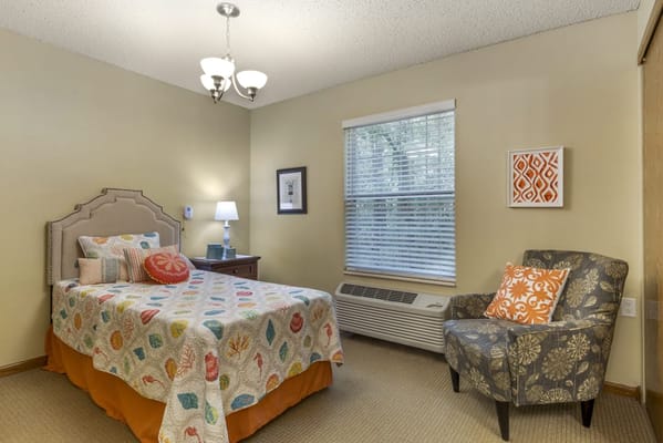 Brightly decorated resident room with a bed and chair