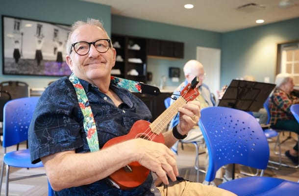 Senior man playing a ukulele in a community room