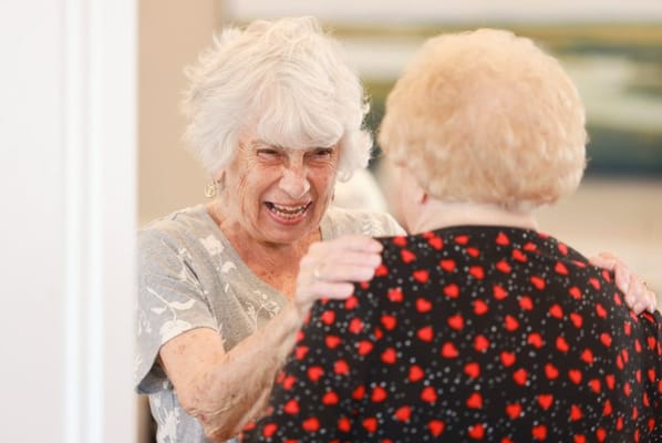 Two elderly women sharing a joyful moment together.
