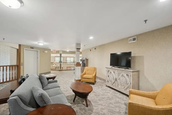 Lounge area with gray sofa, orange armchairs, and TV