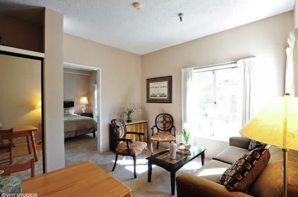 A cozy living room with seating and a view in Garden Court retirement facility.