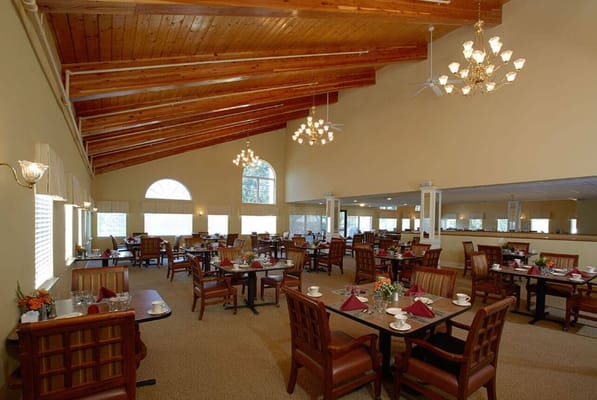 Spacious dining room with tables set for meals and wooden beams overhead