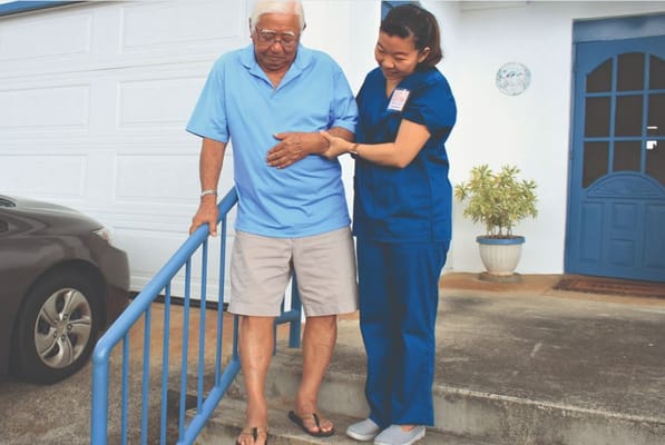 Staff assisting a senior man with mobility outdoors