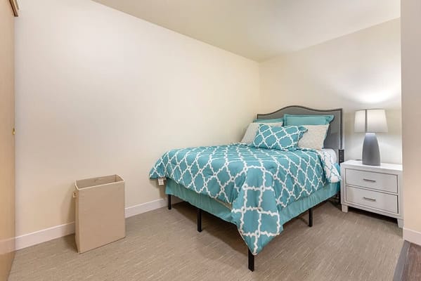 Interior view of a resident room with teal bedding