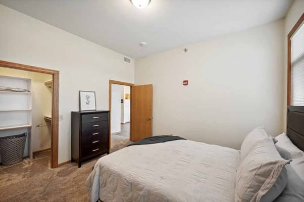 A cozy bedroom with a bed, dresser, and closet