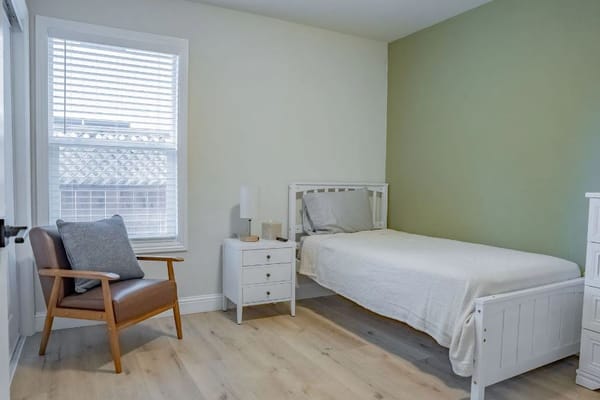 Bright and airy private resident room with a bed and chair