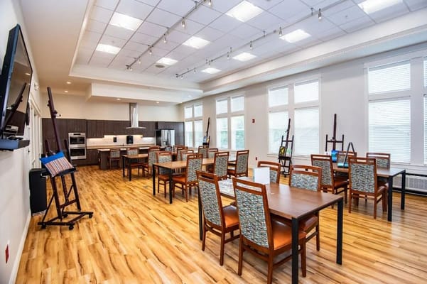 Spacious dining area with wooden tables and chairs in a senior living facility.