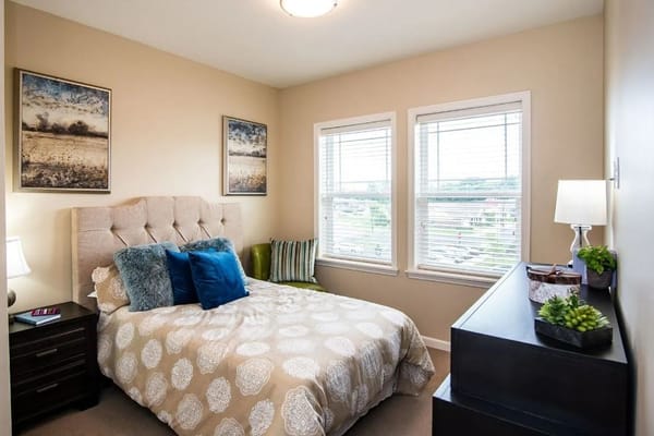 A stylish bedroom with a bed, decorative pillows, and large windows.