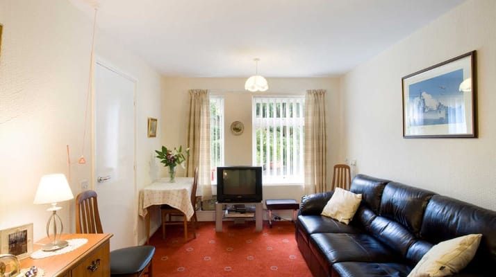 Living room featuring a leather sofa, TV, and a dining table.